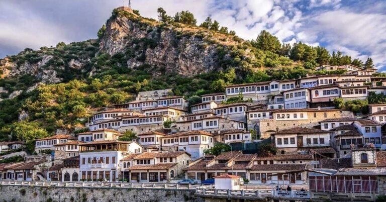 a buildings in the city of berat in albania with lush green hills in the background