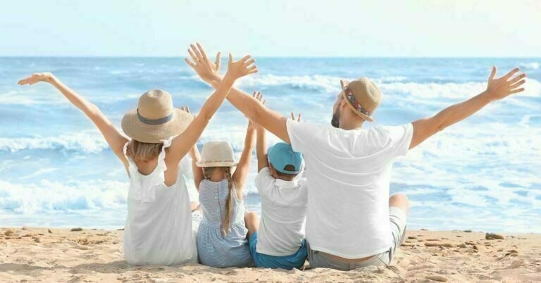 A Happy family Setting on the beach raising hands