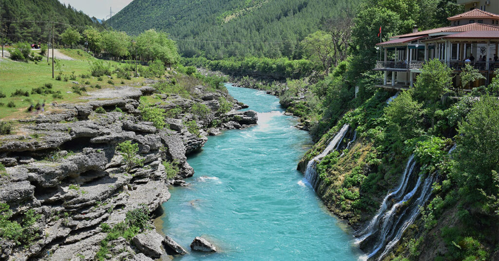 a river running through a lush green hillside in Përmet albania