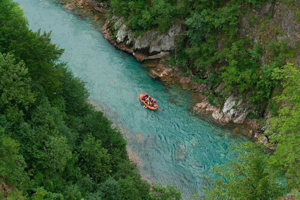 Whitewater Rafting in Montenegro Group rafting on a turquoise river surrounded by lush greenery in Montenegro