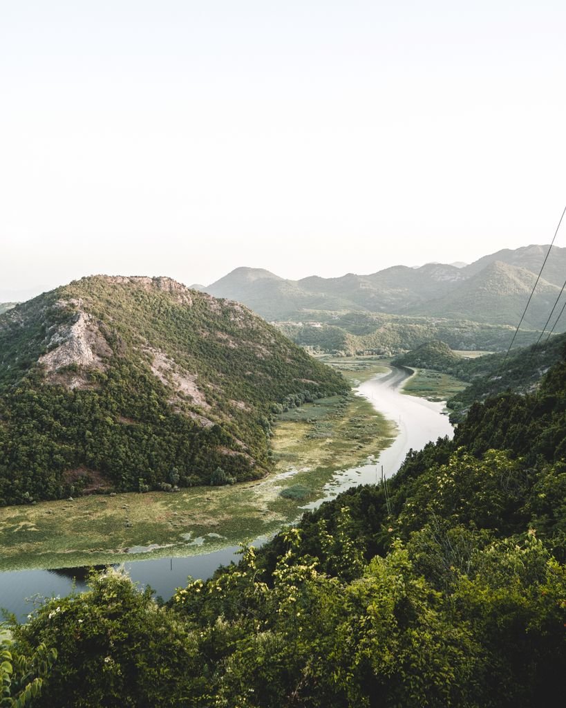 Photo by Artūras Kokorevas Beautiful scenic landscape of Shkodra Lake bend surrounded by lush greenery and mountains in Montenegro.