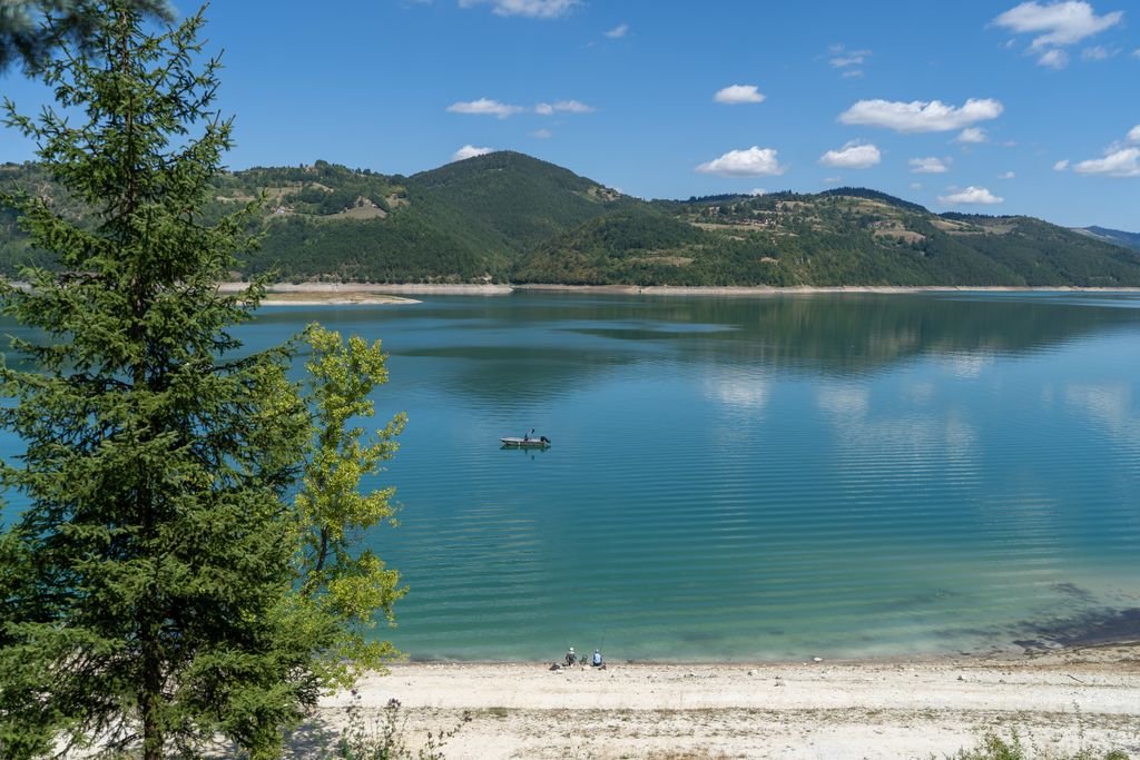Mountain Lake and Boat in Kolašin, Montenegro Tranquil lake surrounded by mountains with a boat in Kolašin, Montenegro